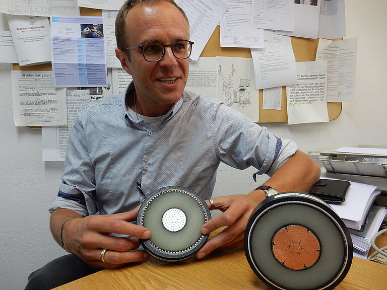 Professor Markus Zink mit zwei Kabelquerschnitten von einer der Stärke, die bei SuedLink zum Einsatz kommt. Zwischen der inneren und der äußeren Leitschicht isoliert Kunststoff.