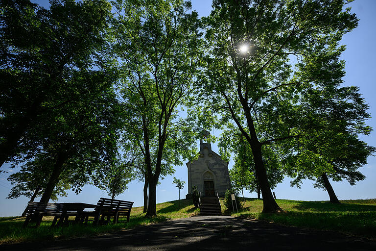 Imposant ragt die sogenannte Schutzmantelkapelle aus den Feldern vor Merkershausen. Hier gibt es Bänke im Schatten mit einem schönen Blick auf das Portal der Kapelle. Imposant ragt die sogenannte Schutzmantelkapelle aus den Feldern vor Merkershausen. Hier gibt es Bänke im Schatten mit einem schönen Blick auf das Portal der Kapelle.