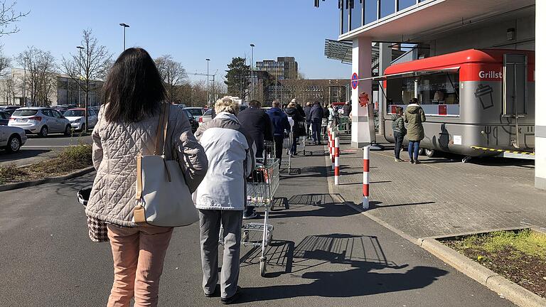 Lange Schlange vor dem Kaufland in Schweinfurt. Ein Ordner lässt nur so viele rein, wie aus dem Supermarkt rauskommen.