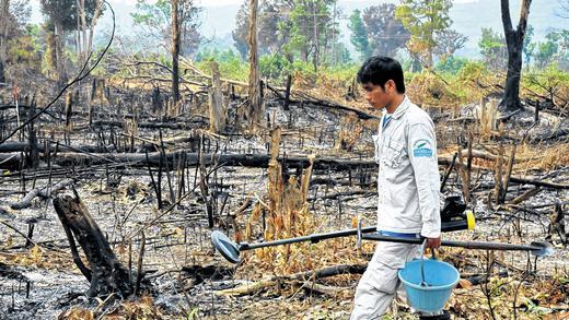 Ein Bombenentschärfer von Handicap International mit Gerät: Teile vom dichten Urwald müssen abgeholzt und niedergebrannt werden, damit der Boden nach Blindgängern abgesucht werden kann. Hier soll später eine Schule gebaut werden.