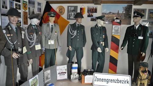 Das Uniformhaus in der Fliedergasse 1 in Ostheim vor der Rhön. Am Eingang muß man sich per Feldtelefon anmelden. Ein Blick in das ehemalige Esszimmer der Familie Greck. Hier zeigt der Sammler seine schönsten Stücke. Ein ganzer Raum befasst sich mit der einstigen deutsch-deutschen Grenze und leitet gleich über zu weiteren Uniformen aus aller Welt. Im Keller des Hauses ist all das zu finden, was Soldaten im Feld so brauchen. Von der Liege über den Schlafsack bis hin zu den Ausrüstungsgegenständen. Aus NVA Beständen ist diese kleine Feldküche, die Manfred Greck ebenfalls zeigen kann. Auch im Außenbereich wird man bereits auf das Uniformhaus in Ostheim/Rhön aufmerksam.