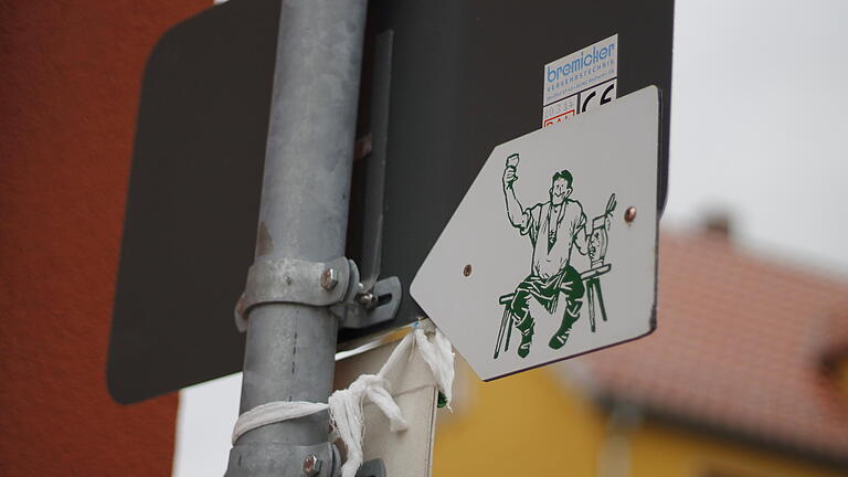 Ein kleines Schild mit einem weintrinkenden Mann darauf auf der Rückseite eines Straßenschildes in Homburg am Freitag, 07. Oktober 2016.