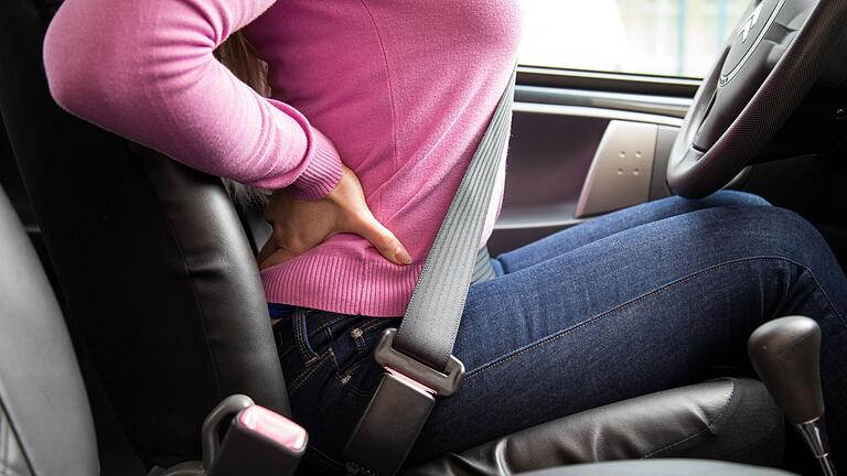 Rückenschmerzen am Steuer       -  Langes Sitzen im Auto kann Rückenverspannungen und Schmerzen verursachen.