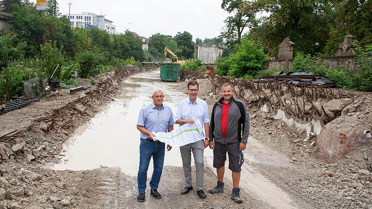 Wo einmal Grün war, kommt wieder Grün hin (von links): Tiefbau-Chef Jörg Roth, Oberbürgermeister Christian Schuchardt, Axel Heer (Brücken- und Ingenieurbau, FA Tiefbau Stadt Würzburg) mit einer Planskizze für die Neuanlage des Geh-, des Zweirichtungsradwegs und des breiten Grünstreifens anstelle der Betonbrücke.