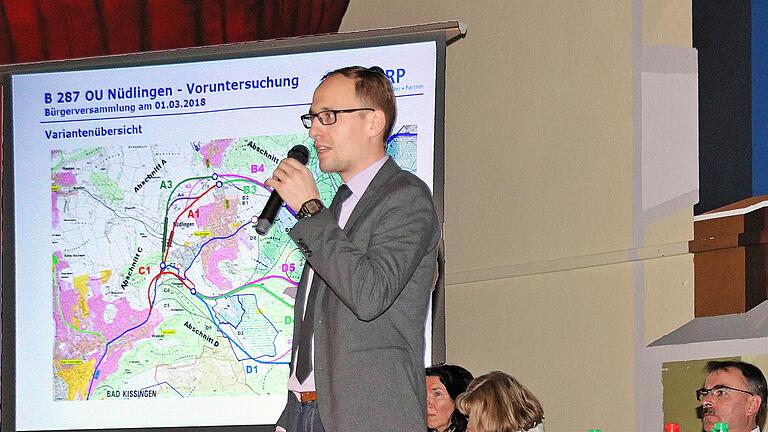 Oberbaurat Alexander Schlegel erklärt die unterschiedlichen Varianten für eine Umgebung um Nüdlingen bei der Bürgerversammlung in der Schulturnhalle Foto: Dieter Britz - Oberbaurat Alexander Schlegel erklärt die unterschiedlichen Varianten für eine Umgebung um Nüdlingen bei der Bürgerversammlung in der Schulturnhalle Foto: Dieter Britz Oberbaurat Alexander Schlegel erklärt die unterschiedlichen Varianten für eine Umgebung um Nüdlingen bei der Bürgerversammlung in der Schulturnhalle Foto: Dieter Britz - Oberbaurat Alexander Schlegel erklärt die unterschiedlichen Varianten für eine Umgebung um Nüdlingen bei der Bürgerversammlung in der Schulturnhalle Foto: Dieter Britz