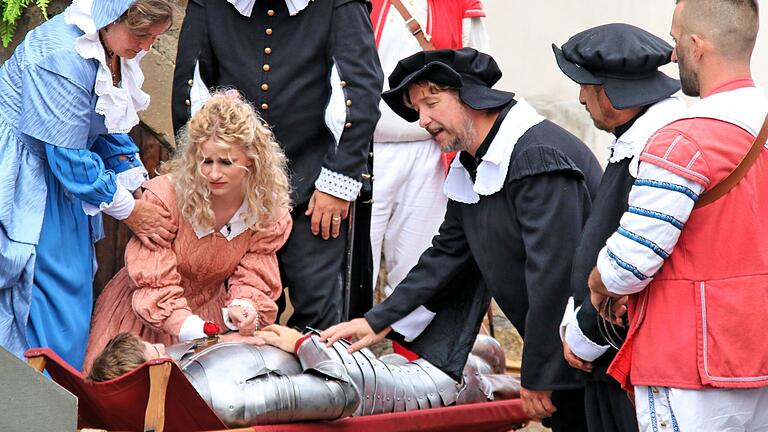 Der verwundete Held wird am Ende des Heimatspiels doch noch gerettet: Szene aus 'Die Schutzfrau von Münnerstadt'. Der verwundete Held wird am Ende des Heimatspiels doch noch gerettet: Szene aus 'Die Schutzfrau von Münnerstadt'.