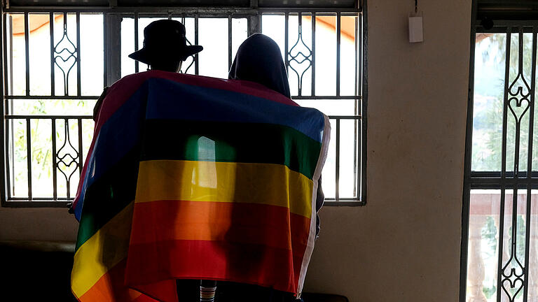 Todesstrafe für Homosexuelle möglich: Gesetz in Uganda unterzeich.jpeg       -  Ein ugandisches Paar bedeckt sich mit einer Pride-Fahne. In dem afrikanischen Land können Homosexuelle mit der Todesstrafe belegt werden.