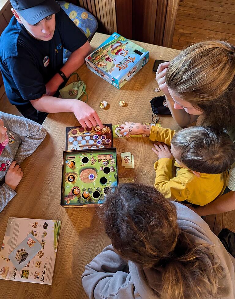 Der ehrenamtliche Spielmobilmitarbeiter Leonard Gräb erklärt beim Spielenachmittag in Altershausen kleinen und großen Spielefans das kooperative Spiel 'Fluffy Valley', bei dem gemeinsam Vorräte für den Winter gesammelt werden müssen.