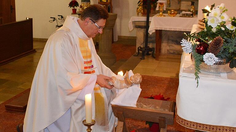 Dekan Andreas Krefft zog mit dem Altardienst und dem Jesuskind in die Kirche von Hohenroth ein. Dann legte er die Figur in die Krippe am Altar.