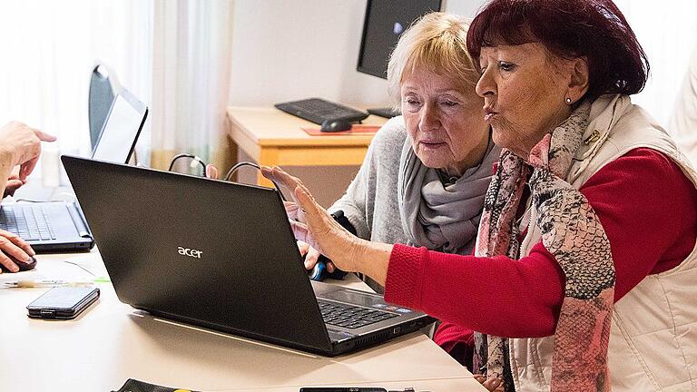 Doris Baumann (links) hilft einer Dame gerade dabei, Fotos von ihrem Handy auf den PC zu übertragen. Im Internetcafé &bdquo;Von Senioren für Senioren&ldquo; des Caritas Seniorenzentrums St. Thekla helfen sich die Damen gegenseitig beim Eintritt in die digitale Welt.