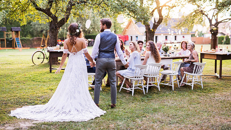 Bride and groom holding hands at wedding reception outside in the backyard.       -  Die standesamtliche Hochzeit hat in den letzten Jahren wieder an Bedeutung gewonnen.