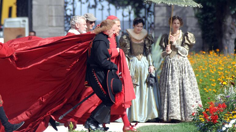 Christoph Waltz alias Kardinal Richelieu auf dem Weg durch den Hofgarten. Sein Kammerdiener, gespielt von dem Würzburger Heribert Kadletz (links hinten), richtet den roten Umgang.