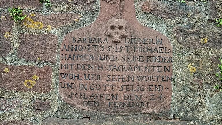 Der Sandstein mit der erneuerten Schrift des Grabmals der Barbara Diener in der Friedhofsmauer.