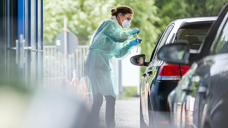 Eine Mitarbeiterin einer PCR-Teststrecke führt auf diesem Symbolbild einen Testabstrich aus.