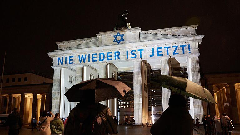 Antisemitismus       -  Der Schriftzug &bdquo;Nie wieder ist jetzt&rdquo; wird zum 85. Jahrestag der Pogromnacht an das Brandenburger Tor projiziert (Archivbild).