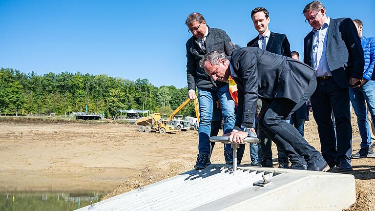 Umweltminister Thorsten Glauber dreht den Abflussschieber am Fuß der neu gebauten Grundsperre zu und startet damit den Wiedereinstau des Ellertshäuser Sees, der seit einem Jahr trocken liegt. Den Kraftakt verfolgen (von links) der örtliche Bürgermeister Friedel Heckenlauer (Stadtlauringen), Schweinfurts Landrat Florian Töpper und CSU-Landtagsabgeordneter Gerhard Eck.