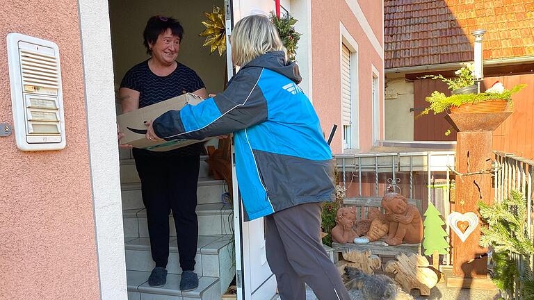 Dankbarkeit und ein kurzes Gespräch an der Tür: Hermes-Botin Karin Engelhardt übergibt in Fröhstockheim ein Paket an Nicole Döblinger (links).