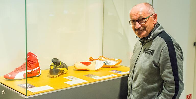 Puma-Archivar Helmut Fischer vor einer Vitrine mit den Schuhen von Michael Schuhmacher, Pelé, Tommie Smith und Usain Bolt (von links). Puma-Archivar Helmut Fischer vor einer Vitrine mit den Schuhen von Michael Schuhmacher, Pelé, Tommie Smith und Usain Bolt (von links).