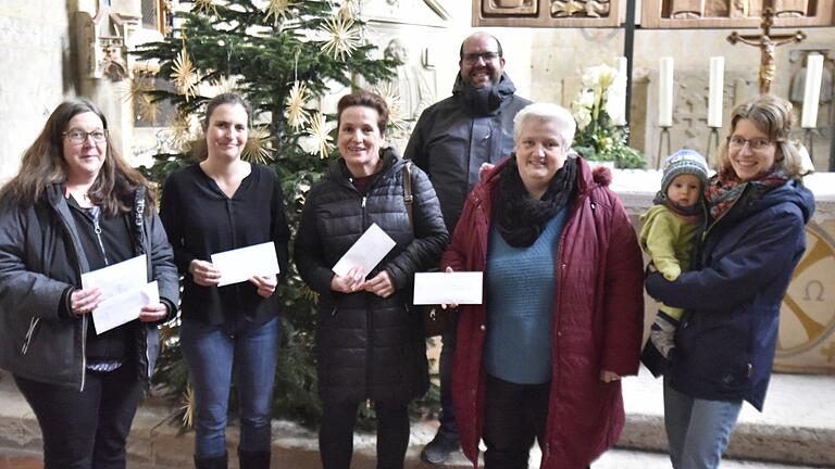 Die Organisatoren des 39. Königsberger Weihnachtsmarktes Anja Fößel  mit Tochter Marie (rechts) sowie Tobias Mäder (hinten) übergaben am Dienstag an Angelika Montag von der evangelischen Kindertagesstätte 'Die Arche'(links), Michaela Bergmann von der BRK-Kita 'Unter der Burg' (2. von links), Rektorin Elke Ankenbrand von der Regiomontanus-Grundschule (Mitte) und Diakonin Sabine Dresel (Zweite von rechts) den Erlös der freiwilligen Spenden für den Besuch der Krippenausstellung in der Marienkirche am Weihnachtsmarkt.