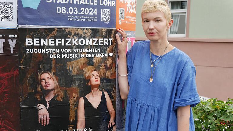 Nina Pearson neben dem Plakat mit dem Duo des Benefizkonzertes in der Alten Turnhalle, das durch ihre Initiative ermöglicht wurde.&nbsp;