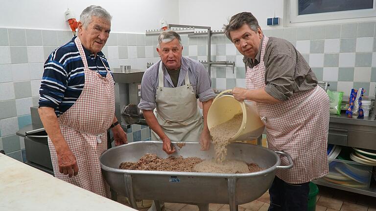 Altbürgermeister Alfred Frank, Dieter Lauter und Johannes Wagenpfahl schütten die gekochte Schweineschwarte mit Zwiebeln in den Fleischtrog Altbürgermeister Alfred Frank, Dieter Lauter und Johannes Wagenpfahl schütten die gekochte Schweineschwarte mit Zwiebeln in den Fleischtrog