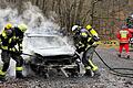 Einsatzkräfte der Feuerwehr Ebern löschen das brennende Auto unter schwerem Atemschutz.