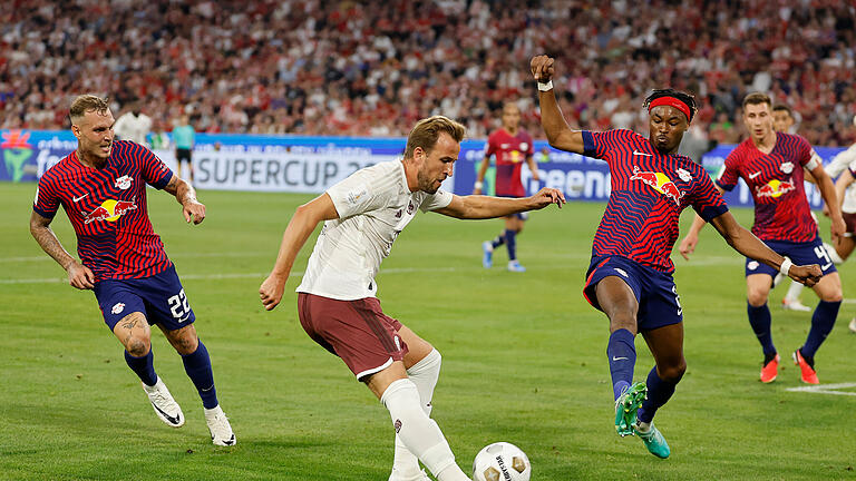 Bayern München - RB Leipzig.jpeg       -  Bayerns Harry Kane (m) versucht sich gegen Leipzigs David Raum (l) und Leipzigs Mohamed Simakan durchzusetzen.