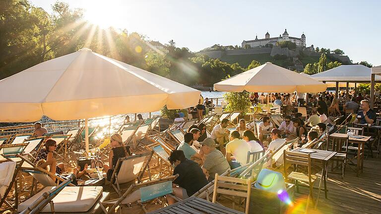 An heißen Tagen besuchen viele Menschen seit 2006 auch den Stadtstrand in Würzburg und genießen den Schatten der Sonnenschirme und kühle Getränke.