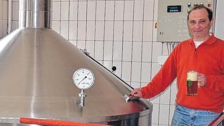 Gunther Hartleb mit einem frisch gezapften Bier neben einem Lagertank in der Brauerei.