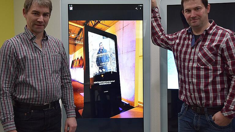 Andreas und Thorsten Hoffmann neben einem Promoscreen in ihrem Ausstellungsraum.