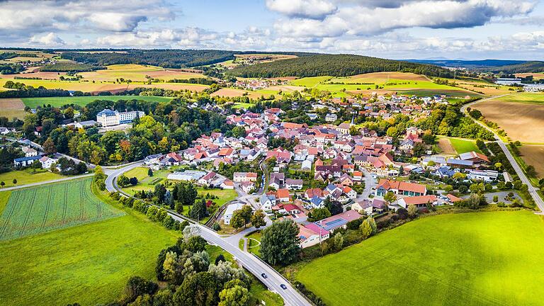 Die Drohnenaufnahme zeigt Untermerzbach mit seinem Schloss, das auf einem Hügel über dem alten Dorfkern steht.