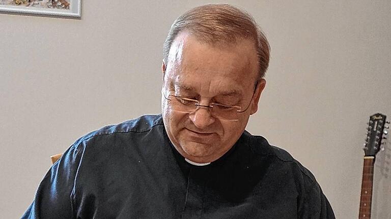 Pfarrer Damian Samulski blättert in der alten Pfarrchronik, welche unter anderem die Hintergründe zur Fußwallfahrt der Gerchsheimer zum Käppele in Würzburg beschreibt.