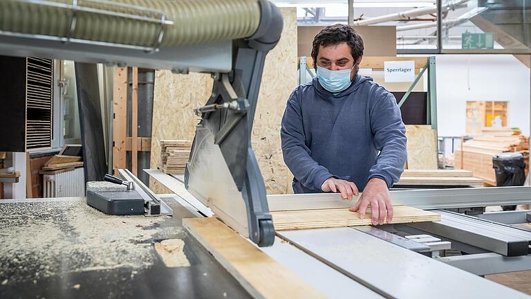 Ein Mitarbeiter der Mainfränkischen Werkstätten, Johann Frank, steht an der Säge und schneidet Holzteile für Paletten zu. Ein Mitarbeiter der Mainfränkischen Werkstätten, Johann Frank, steht an der Säge und schneidet Holzteile für Paletten zu.
