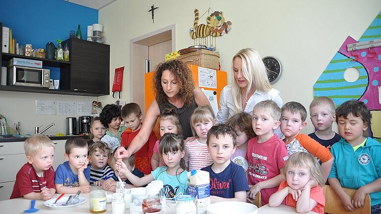 Vorsichtig füllt Sarah unter Aufsicht von Erzieherin Eva-Maria Stühler (links) und Kindergartenleiterin Susanne Stubenrauch zwei Esslöffel fertigen Joghurt in die Becher für den Joghurtbereiter.