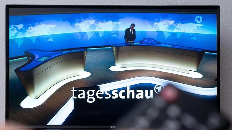 Ein Mann hält eine Fernbedienung vor einen Fernseher, auf dem die Tagesschau läuft. (Symbolbild). Foto: Marius Becker/dpa       -  Viele Tagesschau-Sprecher verdienen ihr Gehalt nicht nur durch das Aufsagen von Nachrichten.