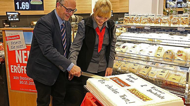 Die Inhaber Roland und Katharina Weber beim Anschneiden der Eröffnungstorte im neuen Kupschmarkt.