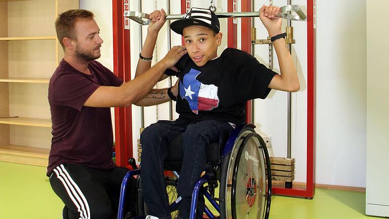 Das Foto zeigt eine Trainingssituation mit Jamie Bernal (16), Schüler der Hans-Schöbel-Schule in Würzburg, mit Physiotherapeut Steffen Herwig am Latzug. Das Foto zeigt eine Trainingssituation mit Jamie Bernal (16), Schüler der Hans-Schöbel-Schule in Würzburg, mit Physiotherapeut Steffen Herwig am Latzug.