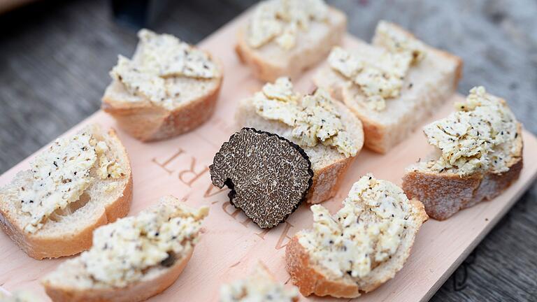 Burgundertrüffel - Der Burgundertrüffel, (Tuber unicatum) gilt ebenfalls als Delikatesse. Hier liegt ein Stück in der Mitte eines Holzbretts zwischen Appetithäppchen mit Trüffelbutter. Burgundertrüffel - Der Burgundertrüffel, (Tuber unicatum) gilt ebenfalls als Delikatesse. Hier liegt ein Stück in der Mitte eines Holzbretts zwischen Appetithäppchen mit Trüffelbutter.