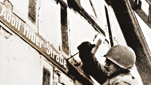 Erste Schritte zur Demokratisierung: Amerikanischer Soldat beim Entfernen eines Straßenschilds. Erste Schritte zur Demokratisierung: Amerikanischer Soldat beim Entfernen eines Straßenschilds.