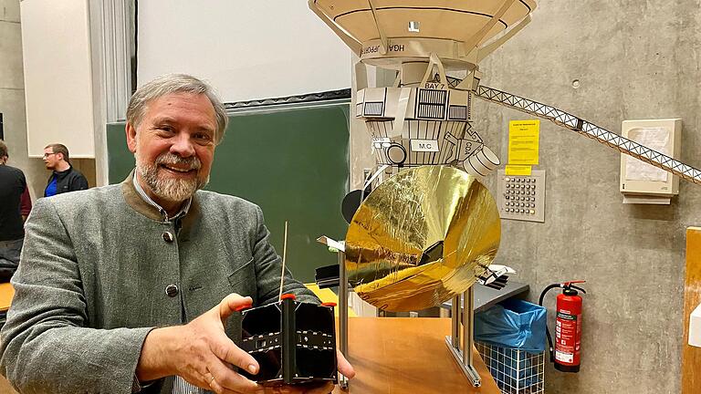 Klaus Schilling, Inhaber des Lehrstuhls für Robotik und Telematik an der Uni Würzburg, nach seiner Abschiedsvorlesung. In der Hand hält er den Kleinsatelliten UWE 4. Rechts ein Modell der Raumsonde Huygens aus seiner Antrittsvorlesung von 2005,