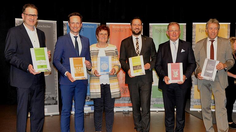 Die Redner beim Festkommers 800 Jahre Werneck mit den sechs Bänden der druckfrischen Ortschronik (von links): Stefan Menz, Vorsitzender des Historischen Vereins Heidenfeld, Landrat Florian Töpper, die Vorsitzende des Organisationsteams Edeltraud Baumgartl, Bürgermeister Sebastian Hauck, Bezirkstagspräsident Erwin Dotzel und Bernd Göbel, Vorsitzender des Historischen Verein Werneck.