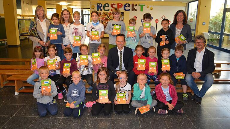 Landrat Florian Töpper (Mitte) übergab stellvertretend für alle Zweitklässler im Landkreis der Klasse 2a der Gerolzhöfer Grundschule die Möhrchenhefte. Mit dabei waren Schulamtsdirektorin Gabriele Freiberg (links),&nbsp; sowie Regionalmanagerin am Landratsamt Johanna Böhm (Dritte von links hinten), Klassenleiterin Heike Schmitt (hinten rechts) und Schulrektor Helmut Schmid.