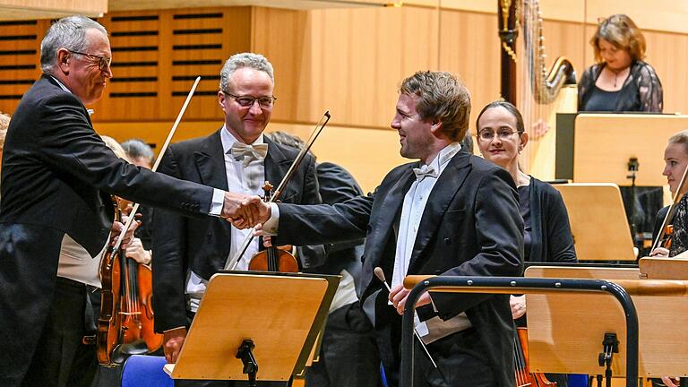Der Mann links vom Dirigenten: Konzertmeister Franz Peter Fischer und Erster Kapellmeister Gábor Hontvári geben einander nach einem Konzert im Jahr 2022 dem Brauch gemäß die Hand. Der Mann links vom Dirigenten: Konzertmeister Franz Peter Fischer und Erster Kapellmeister Gábor Hontvári geben einander nach einem Konzert im Jahr 2022 dem Brauch gemäß die Hand. 