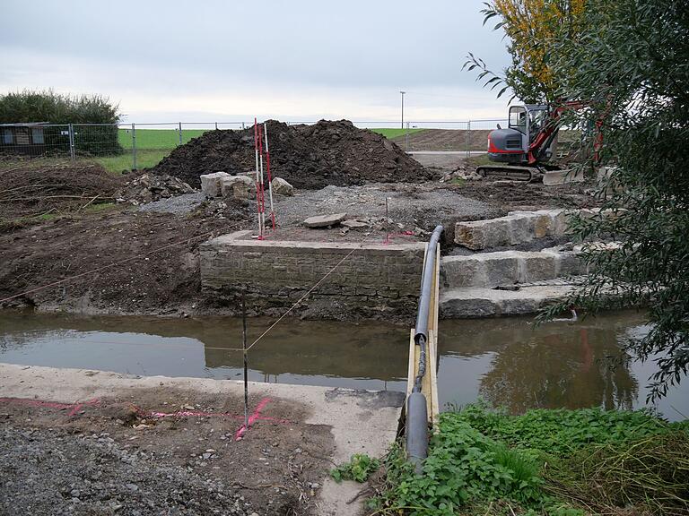 Ein aktuelles Baustellenfoto an der Pleichach in Oberpleichfeld beweist, dass noch viel zu tun ist. Die kleine Brücke wurde abgerissen und wird als Fußgängerbrücke auf den bisherigen Brückenfundamenten neu gebaut. Das Bachbett wird an mehreren Stellen aufgeweitet und die Muschelkalkquader sollen einmal ein Mischpflaster aus Granit und Basalt bekommen.