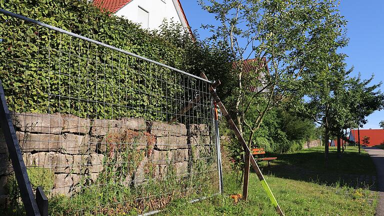 Schutzzäune hat die Stadt im Baugebiet Hündlein vor den Stellen postiert, wo die Bruchsteinmauer sich gefährlich neigt.