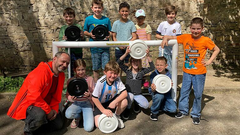 Dieter Metzger, Hausmeister der Grundschule Würzburg-Stadtmitte, und begeisterte Schulkinder mit Spielsteinen vor dem neu gekauften Fußballtor.