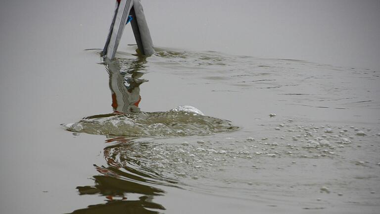 Nur die Luftblasen deuten darauf hin, dass unten im trüben Main Taucher der Wasserwacht gegen die starke Strömung kämpfen, um die Achsen des versunkenen Autos mit starken Seilen zu versehen. Nur die Luftblasen deuten darauf hin, dass unten im trüben Main Taucher der Wasserwacht gegen die starke Strömung kämpfen, um die Achsen des versunkenen Autos mit starken Seilen zu versehen. 