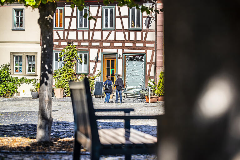 Zwei Passanten stehen vorm 'Café im Kunsthandwerkerhof' am Marktplatz.