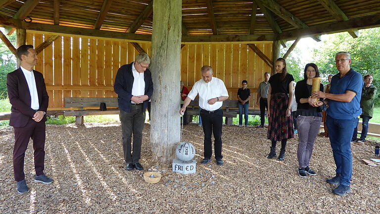 Zum Abschluss der Einweihungsfeier des Friedensforums segnete Pfarrer Stephan Mai das Denkmal für den Frieden. Im Bild, von links: Bürgermeister Thorsten Wozniak, Pfarrer Reiner Apel, Pfarrer Stefan Mai, Amelie Auer und Besucher, die das Friedenslicht trugen.