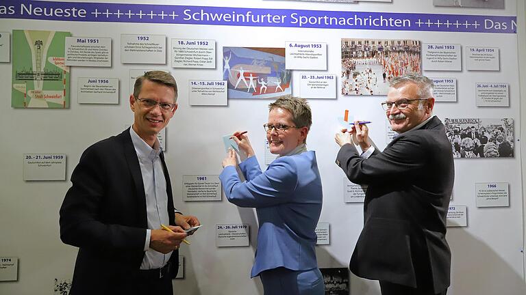 Schrieben gleich ihre wichtigsten Sportnachrichten auf: Bei der Eröffnung der Ausstellung Made in SW - Schweinfurt Stadt des Sports verewigten sich (v.l.) Oberbürgermeister Sebastian Remelé, Kuratorin Daniela Kühnel und Landesturnfest-OK-Chef Andy G. Krainhöfner an der raumhohen Schauwand mit Schweinfurter Sportnachrichten aus 170 Jahren Sportgeschichte in der Stadt.